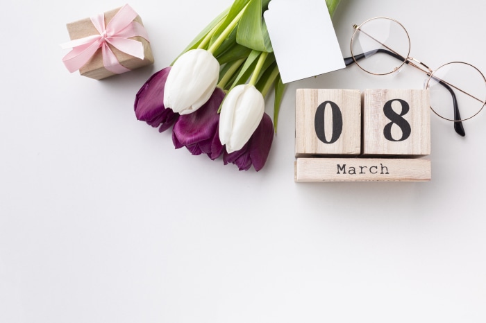 Wooden calendar showing March 8, tulips, gift, and glasses