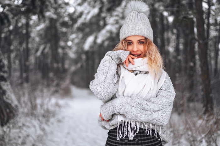 Woman in winter hat and sweater in snowy forest