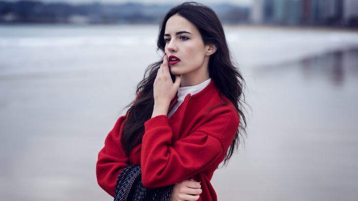 Woman with black hair in red jacket on beach