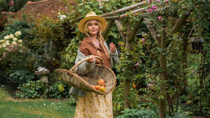 Woman in straw hat holding basket of apples in garden