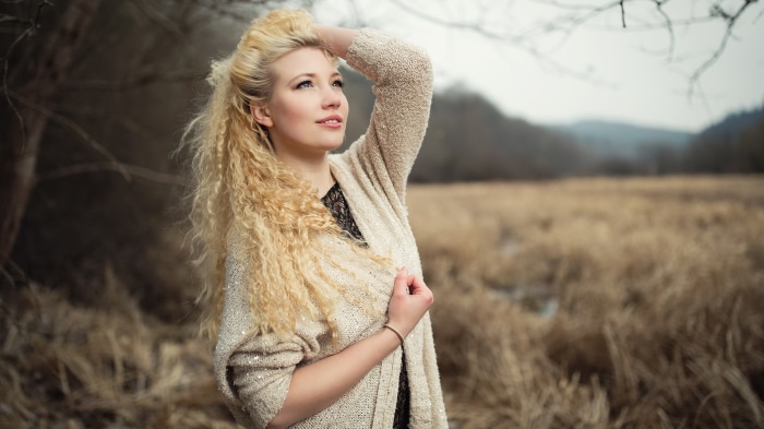 Woman with blonde curly hair in a field