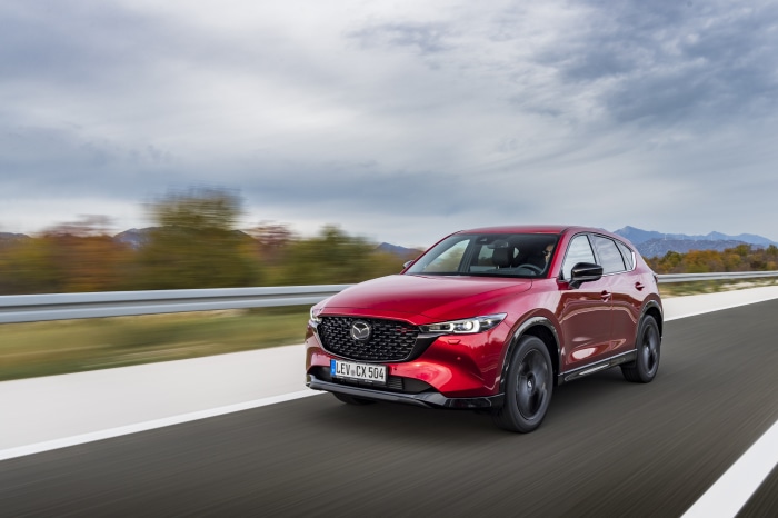 Red Mazda CX-5 SUV driving on a road