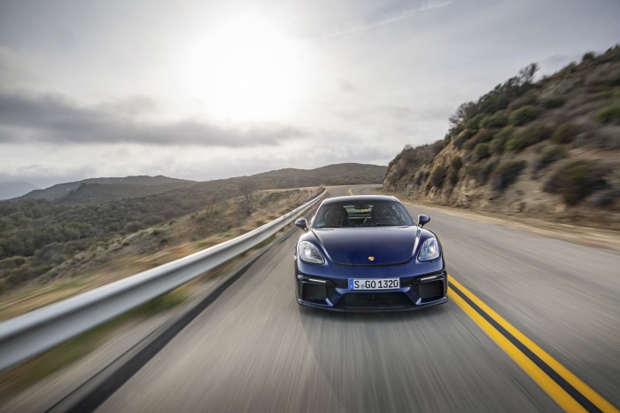 Blue Porsche 718 Cayman GT4 on a winding road