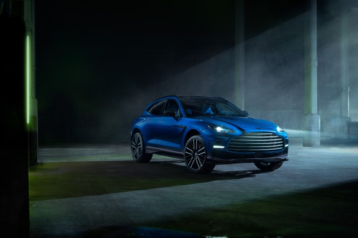 Blue Aston Martin DBX707 SUV in a dark industrial setting
