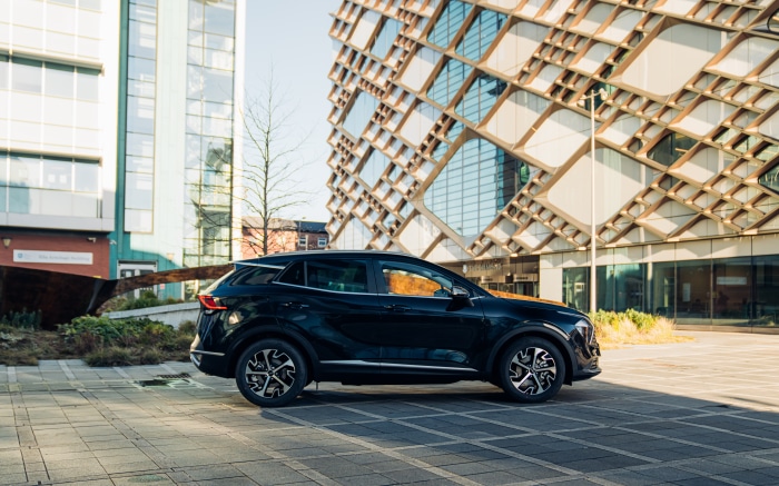 Black Kia Sportage SUV parked near modern buildings