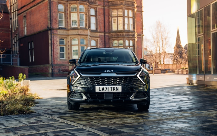 Black Kia Sportage SUV parked in front of a brick building