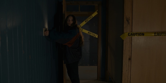 Havana Rose Liu in a dark room with caution tape