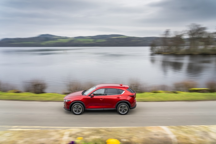 Red Mazda CX-5 SUV driving by a lake