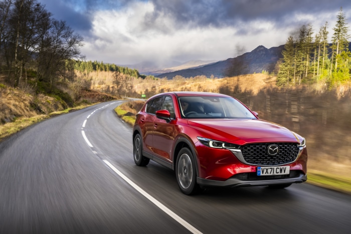 Red Mazda CX-5 driving on a winding road in Scotland
