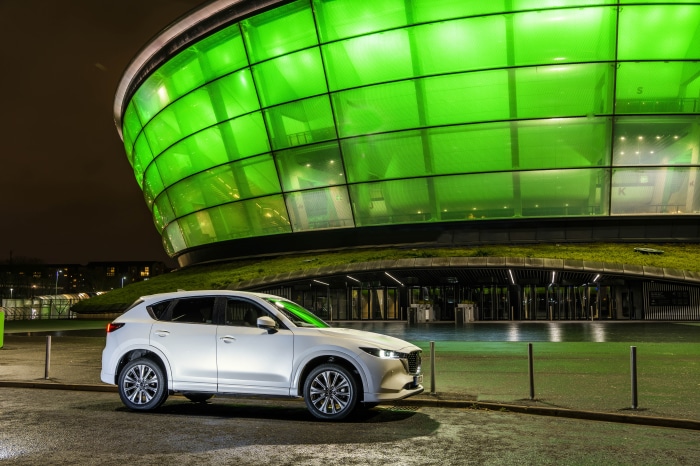 White Mazda CX-5 parked in front of a green illuminated building
