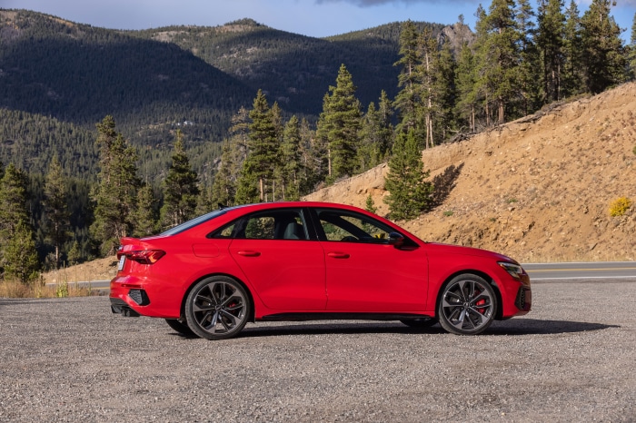 Red Audi A3 Sedan parked on gravel road with mountains