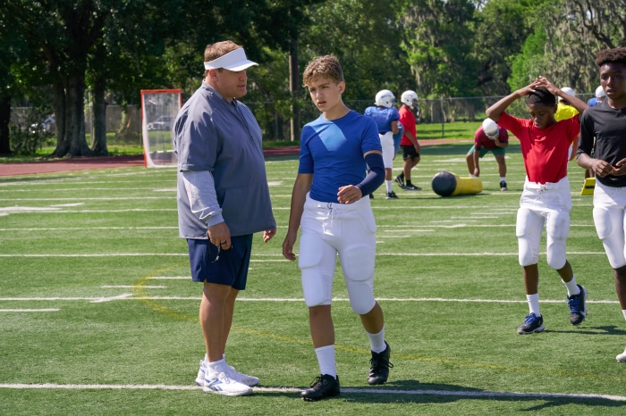 Kevin James and a young football player on a field