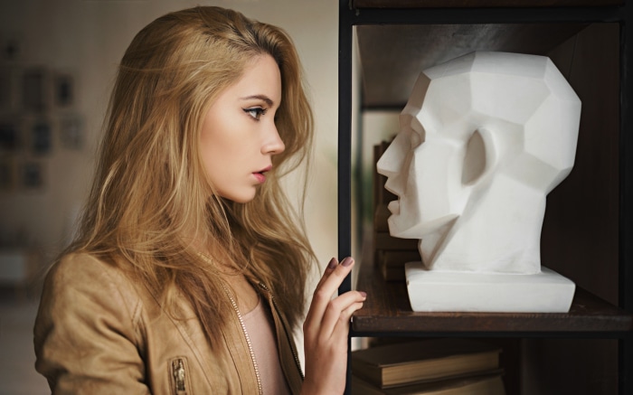 Woman looking at a geometric head sculpture