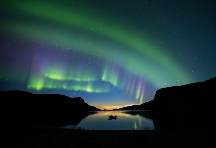 Aurora Borealis over a lake with a boat
