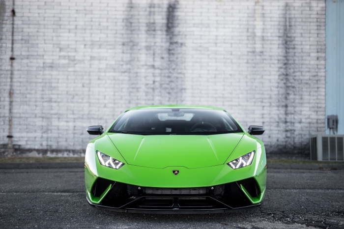 Green Lamborghini Huracán Performanté parked in front of a brick wall