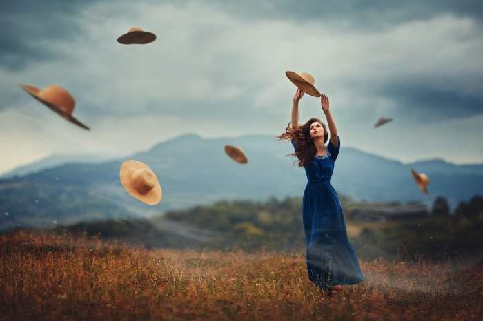 Woman in blue dress with hats flying in the wind