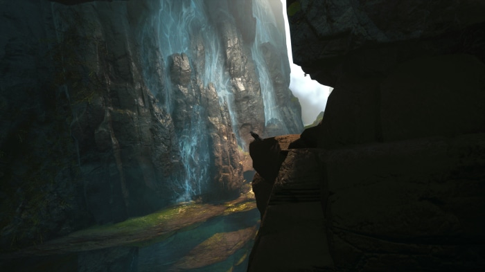 A bird perched on a cliff overlooking a waterfall in a canyon
