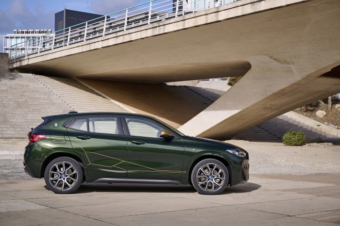 Green BMW X2 xDrive25e parked under a concrete bridge
