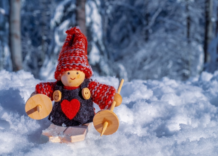 Wooden toy gnome with red hat in snow