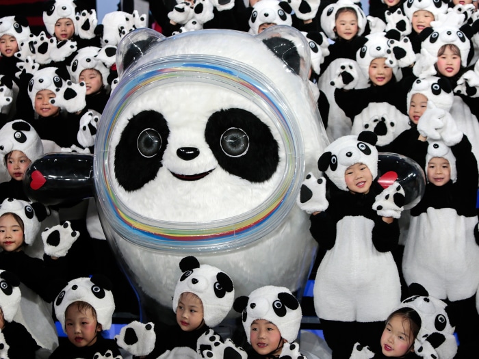 Bing Dwen Dwen mascot with children in panda costumes