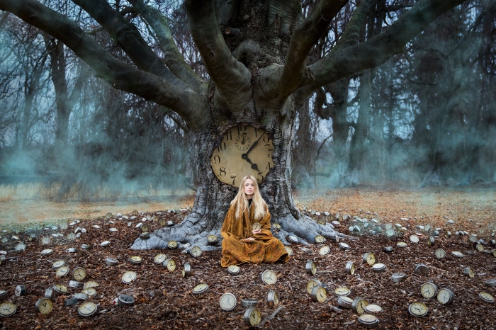 Woman sitting under a giant tree with a clock
