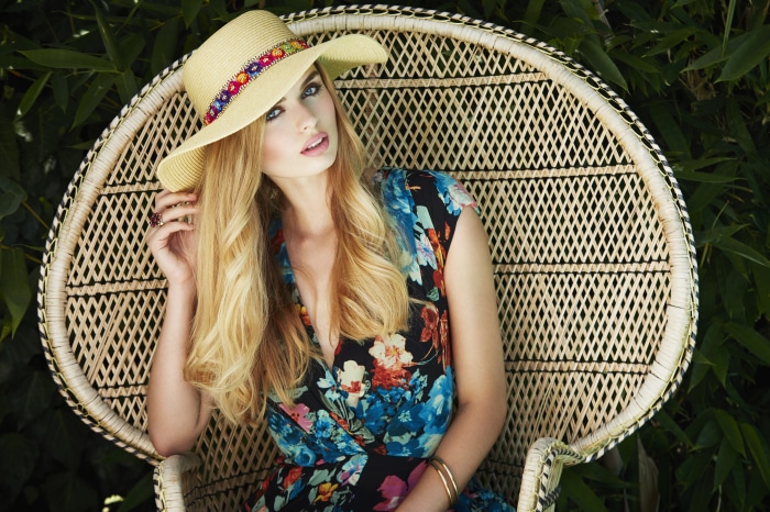 Model in a hat and floral dress sitting in a chair