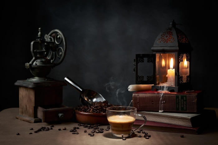 Still life with coffee grinder, coffee beans, and candle lantern
