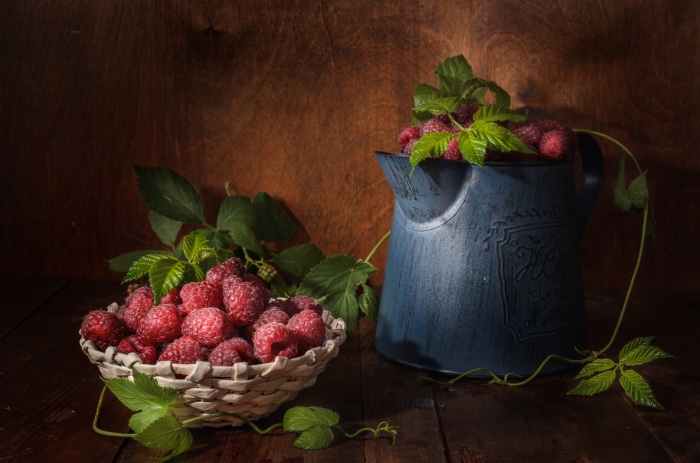 Still life with raspberries in a basket and pitcher