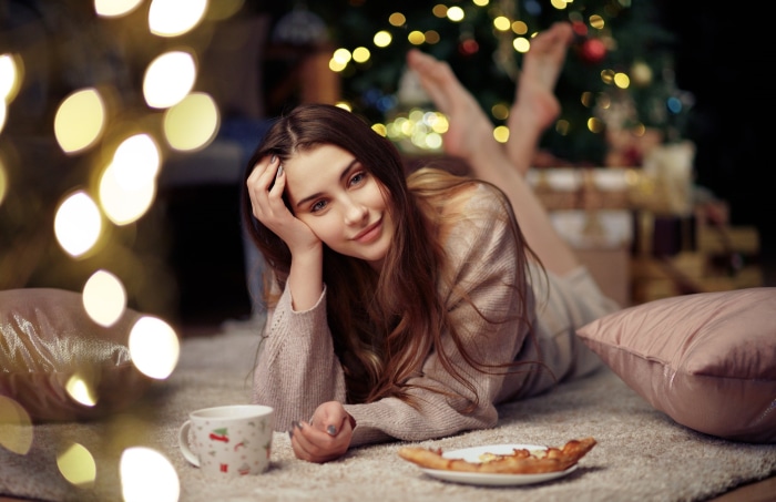 Brunette woman lying down with Christmas tree