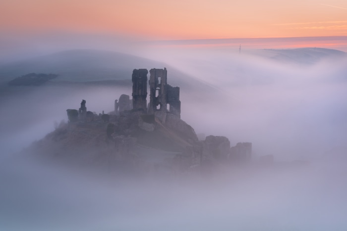Castle ruins in fog at sunrise