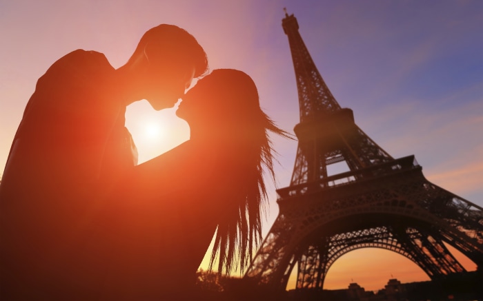 Couple kissing in front of the Eiffel Tower at sunset