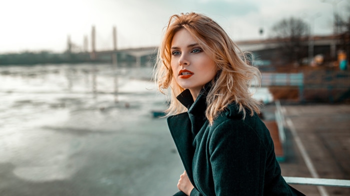 Woman with blonde hair and red lipstick wearing a coat