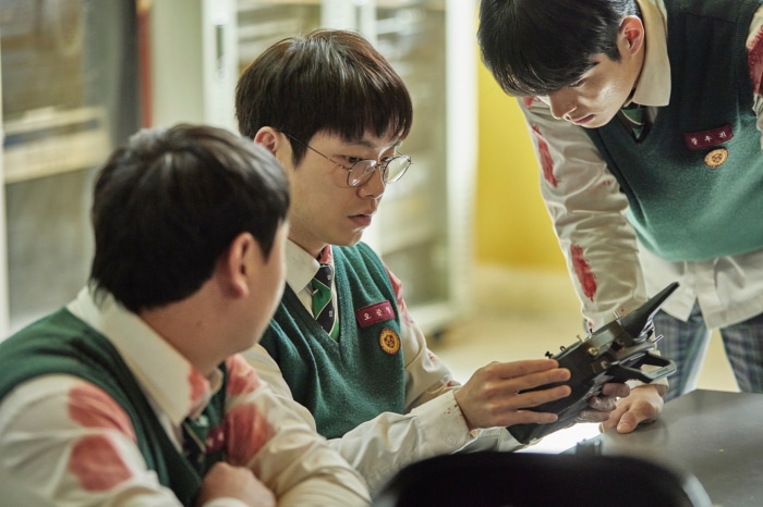 All Of Us Are Dead students examining device