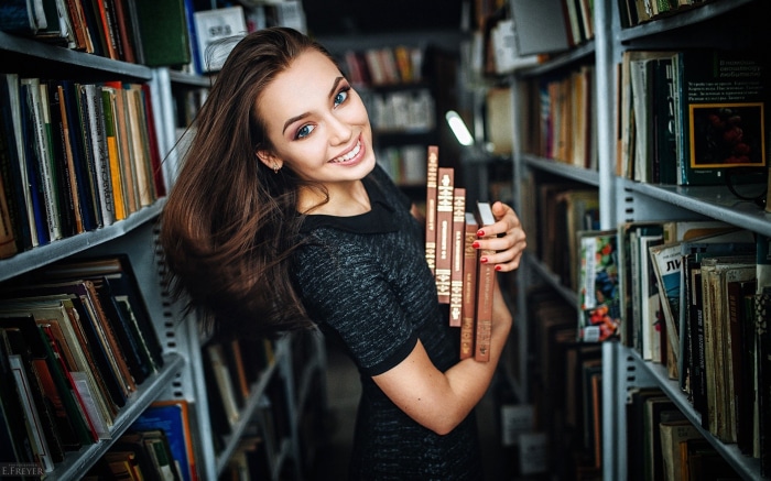 Brunette woman holding books in a library