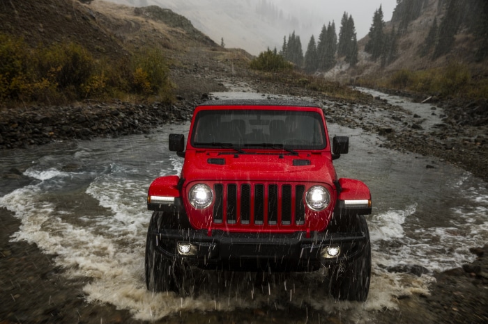 Red Jeep Wrangler driving through a stream