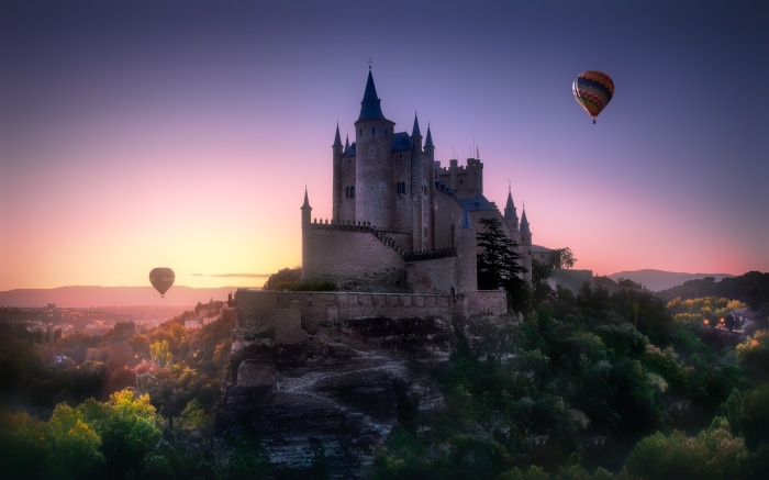 Castle and hot air balloons at sunset