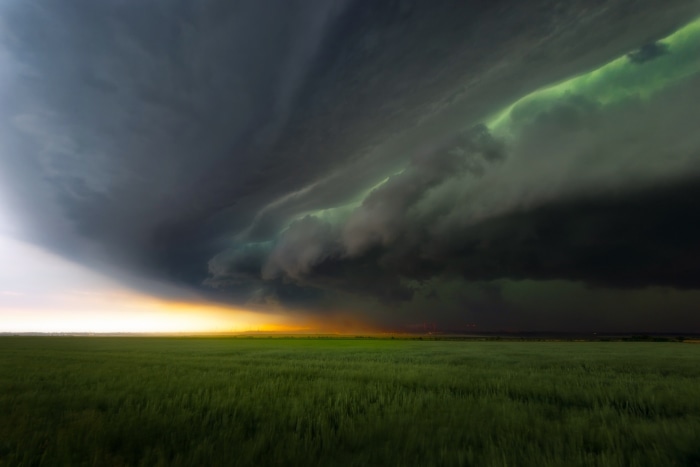Stormy clouds over a green field at sunset
