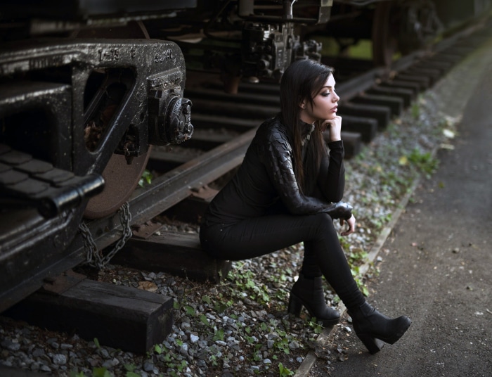 Woman with black hair sitting on train tracks