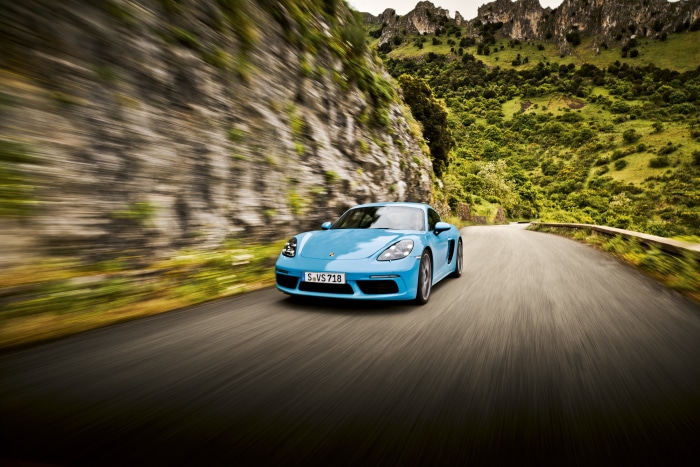 Blue Porsche Cayman driving on a mountain road