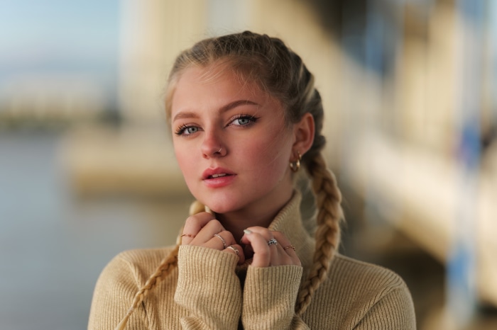 Young woman with blonde braids wearing a tan turtleneck