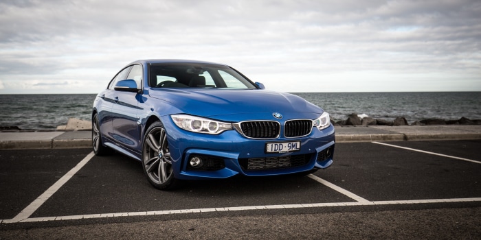 Blue BMW 4 Series parked by the ocean