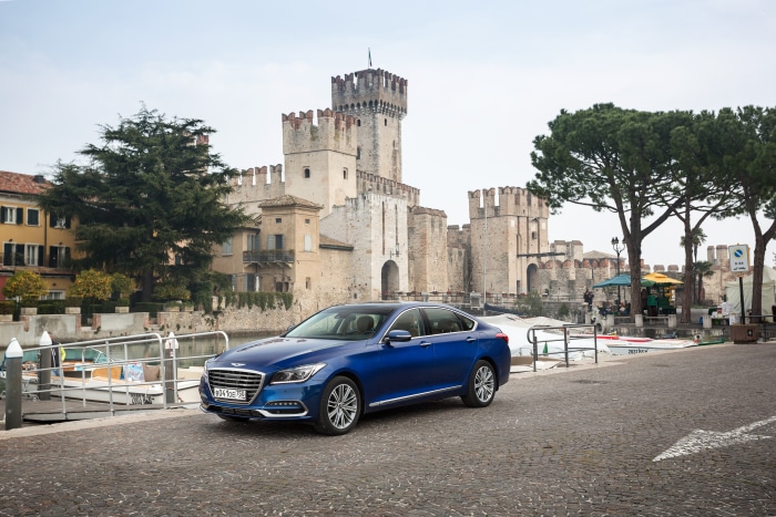 Blue Genesis G80 Sedan parked near a castle
