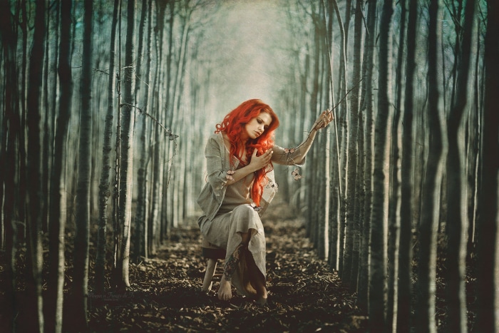 Woman with red hair sitting in a forest
