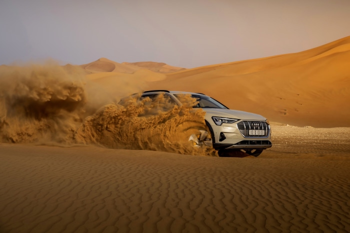 Audi E-Tron SUV driving through desert sand dunes