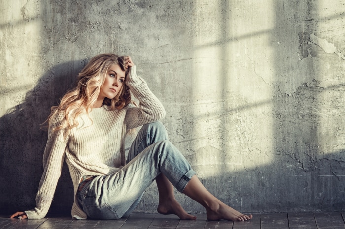 Woman in sweater and jeans sitting on floor