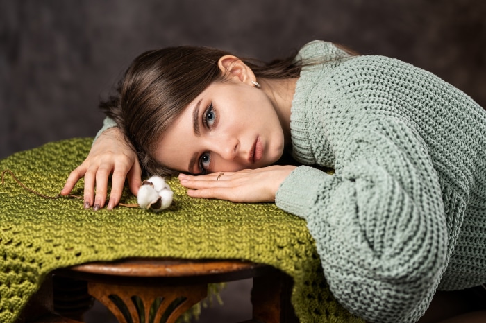 Young woman with cotton flower on green blanket