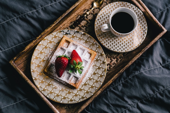 Waffle with strawberries and coffee on a tray