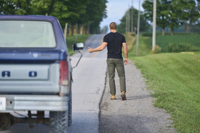 Alan Ritchson as Reacher hitchhiking
