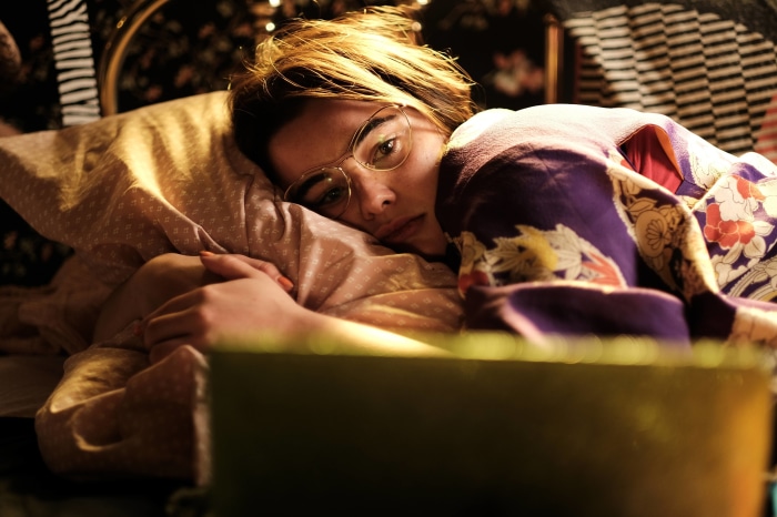 Woman in kimono lying on bed with glasses