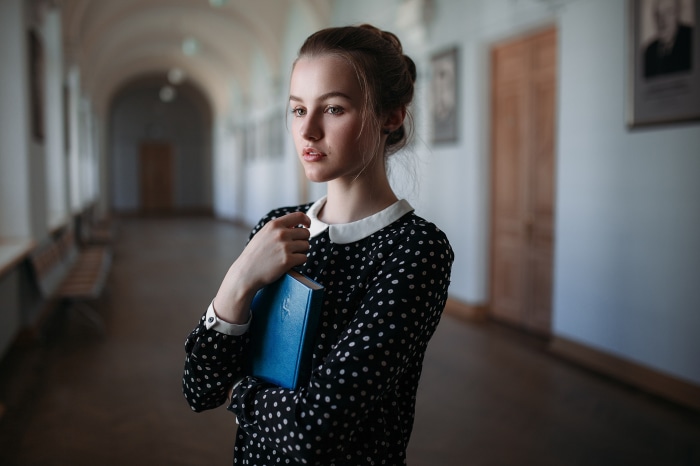 Young woman holding a blue book in a hallway